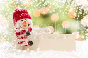 snowman with blank white card over abstract snow and light