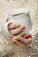 woman with red and green nail polish holding cup of coffee