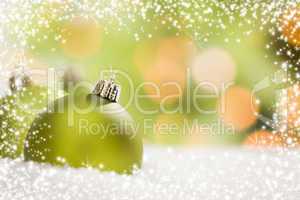 green christmas ornaments on snow over an abstract background