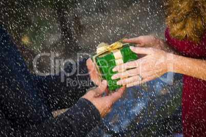 hands of man and woman exchanging christmas gift in snow