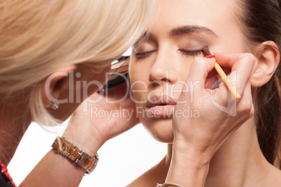 beauty stylist applying make-up to a young model
