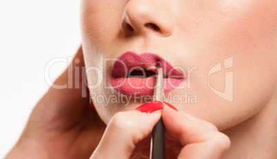 stylist applying lip gloss to a young woman