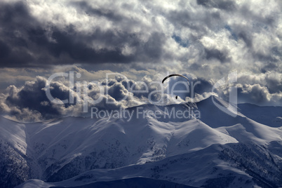 evening mountain with clouds and silhouette of parachutist