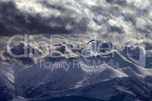 evening mountain with clouds and silhouette of parachutist