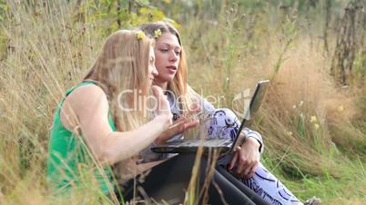 Female friends with laptop outdoor.