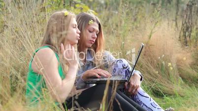 female friends with laptop outdoor.