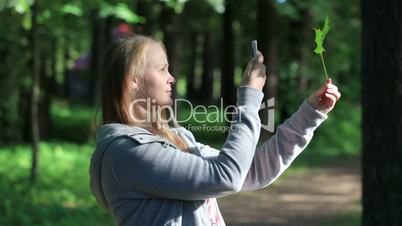 Young woman taking a picture of leaf.