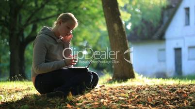 young woman sitting on the ground outdoors