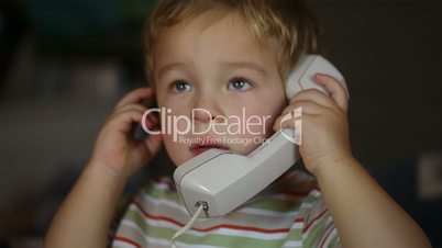excited little boy talking over telephone receiver