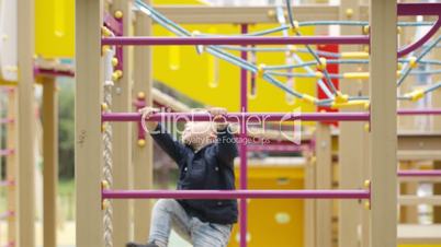 Cute little boy climbing on a jungle gym