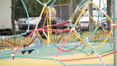 happy little boy climbing on playground equipment