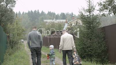 two men and a boy walking in the countryside.