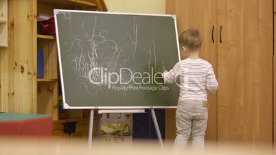Little boy drawing on a chalkboard at kindergarten