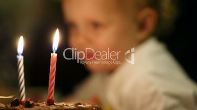 little boy blowing out two candles on his birthday cake