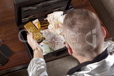 man with suitcase full of money and gold