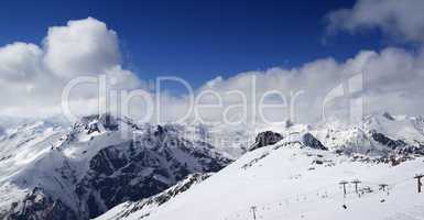 panoramic view on ski slope and cloudy mountains at nice sun day