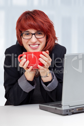 woman sitting on laptop and drinking from the cup