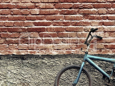 Old rusty vintage bicycle leaning against a brick wall