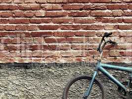 Old rusty vintage bicycle leaning against a brick wall