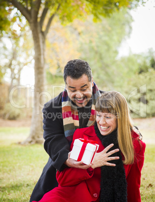 mixed race couple sharing christmas or valentines day gift outsi