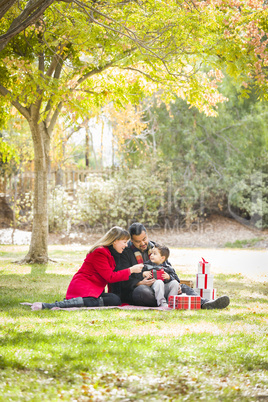 mixed race family enjoying christmas gifts in the park together