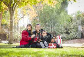 mixed race family enjoying christmas gifts in the park together