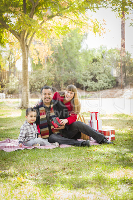 mixed race family giving gifts in the park together