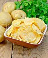 chips in a bowl with a potato on the board