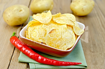 chips in a bowl with hot peppers and potatoes on board