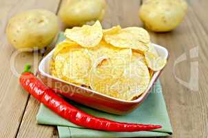 chips in a bowl with hot peppers and potatoes on board