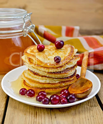 flapjacks with cranberry and a jar of honey on the board