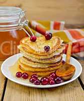 flapjacks with cranberry and a jar of honey on the board