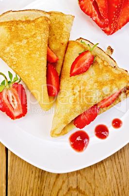 pancakes with strawberries and jam on a white plate