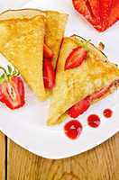 pancakes with strawberries and jam on a white plate