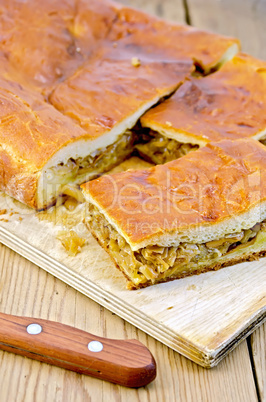 pie with cabbage and mushrooms on a board with a knife