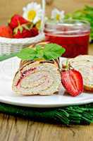 Roulade with a jar of jam and strawberries on a board