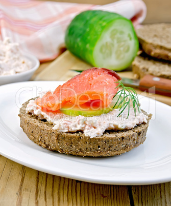 Sandwich with cream and salmon with cucumber on the board