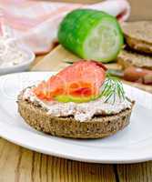 Sandwich with cream and salmon with cucumber on the board