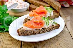 Sandwich with salmon and cream in a dish with cucumber