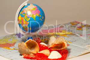 seashells and small globe on a book with a geographical map.