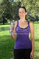 Junge Frau mit Trinkflasche beim Sport oder Joggen