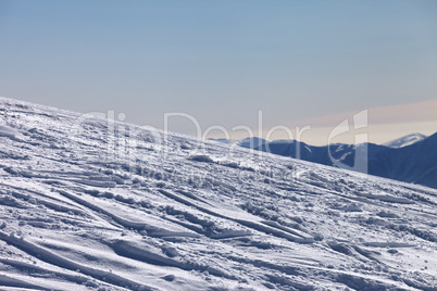 ski slope with trace from ski and snowboards in newly - fallen s