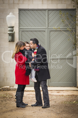 warmly dressed family loving son in front of rustic building