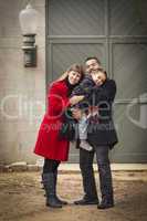 warmly dressed family loving son in front of rustic building