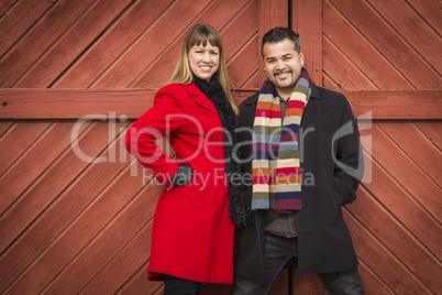 mixed race couple portrait in winter clothing against barn door