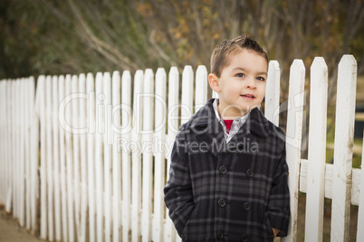 young mixed race boy waiting for schoold bus along fence outside
