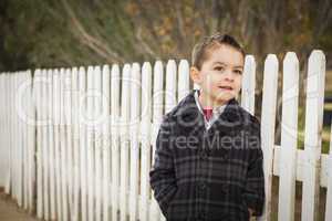 young mixed race boy waiting for schoold bus along fence outside