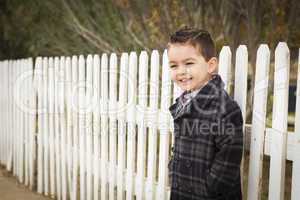 young mixed race boy waiting for schoold bus along fence outside