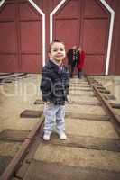 mixed race boy at train depot with parents smiling behind