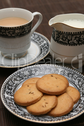 plate full of biscuits served with milk pot and a cup of tea